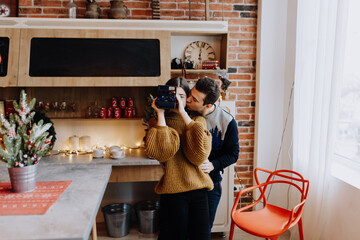 young couple is photographed hugging in the kitchen during Christmas