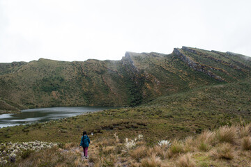 Obraz premium Woman walking through paramo mountain path in a cloudy day