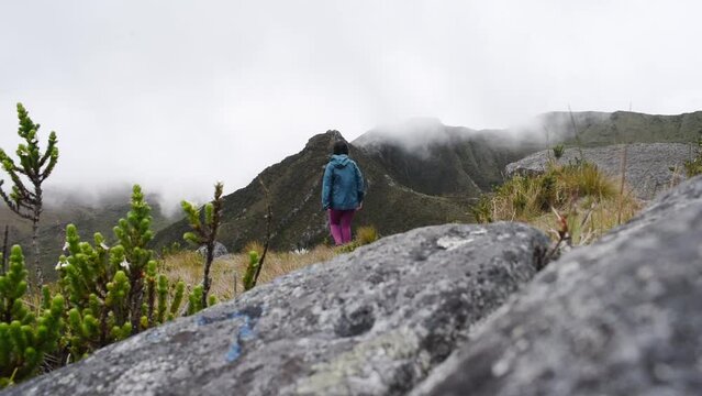 Woman walking through paramo mountain path in a cloudy day