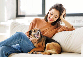 cheerful woman hugging her beloved pet dog at home on the couch. - 610193471