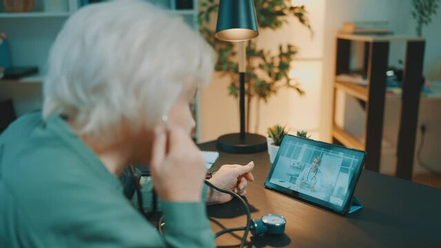 Old female monitoring blood pressure with tonometer, consulting therapist online