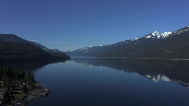 Aerial Serenade of Slocan Lake's Tranquil Blue Expanse Framed by Snow-Capped Peaks