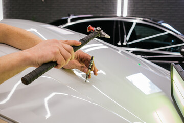 A specialist repairs a dent on the car body without painting. PDR. Process of paintless dent repair...