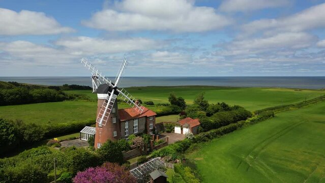 Wide aerial view of a windmill set in the English countryside with the sea behind. Weybourne, Norfolk, UK.