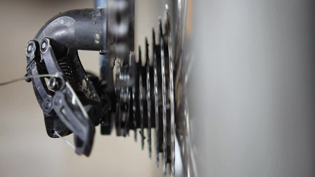 Close-up of a bike chain running through a rear derailleur tensioner roller and down a cassette from a small chainring to a large sprocket. Bicycle transmission and cassette. Bicycle repair