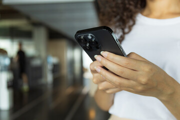 Young woman holding phone in office, space for text