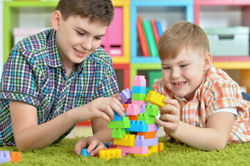 brothers playing with colorful plastic blocks in room