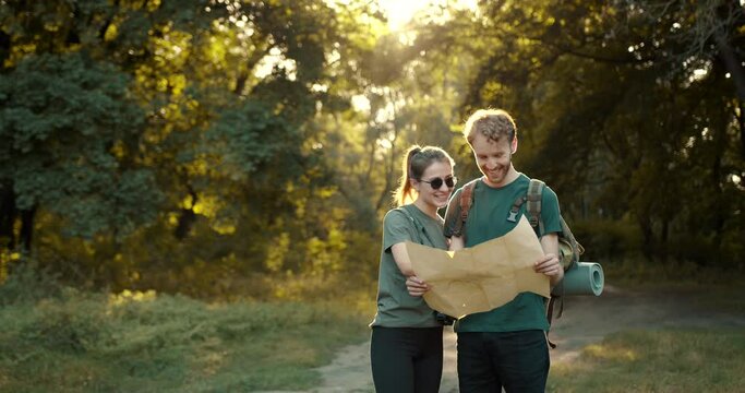 Couple hikers look at map in the forest