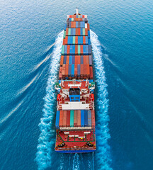 Aerial front view of a loaded container cargo vessel traveling over ocean.