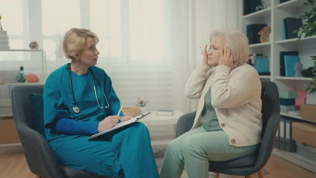 Elderly woman complaining to doctor about headache, home healthcare services