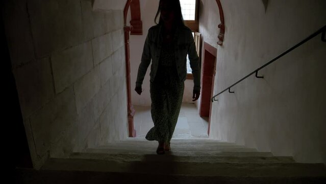 Woman walking up the stairs in a dark hallway.