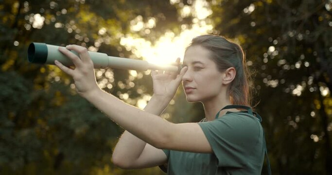 Hiker standing in the forest and looking through telescope