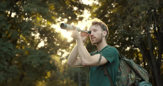 Hiker standing in the forest and looking through telescope