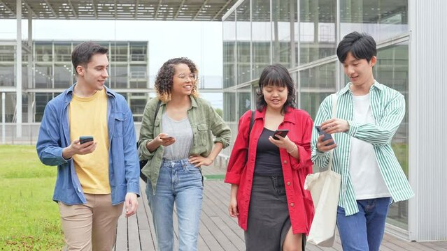Multinational youth group walking with smart phone in college campus. College students.