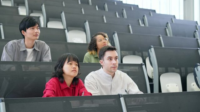 A group of multinational students taking a lecture in an auditorium. international education.