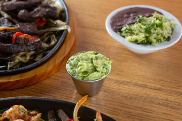 A view of a metal condiment cup of guacamole.