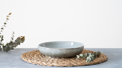 Table setting with ceramic plate and eucalyptus branches on blue background. Minimal style concept.