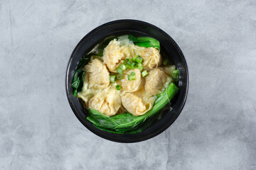A top down view of a bowl of wonton soup.