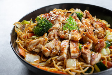 A closeup view of a bowl of chicken yakisoba noodles.