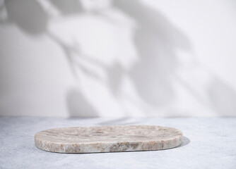 Marble oval board with shadow of plants on a light background for product demonstration. Trendy...