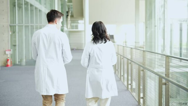 Multinational group walking in the lobby wearing white coats.