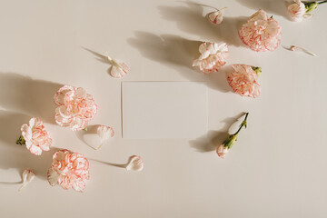 Blank paper sheet card with mockup copy space and carnation flowers on white background. Aesthetic...