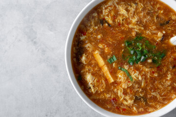 A top down view of a bowl of hot and sour soup.