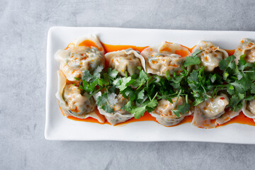 A top down view of a plate of spicy wontons.