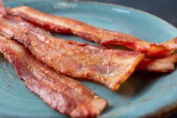 A closeup view of a plate of bacon strips.