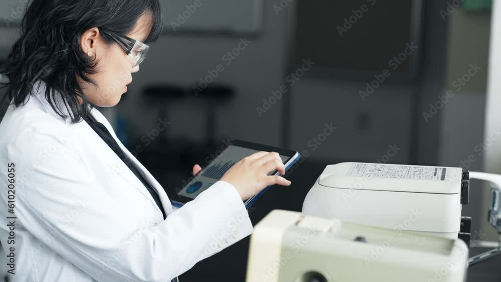 Poster A researcher using experimental equipment while looking at a tablet screen. Research and Development.