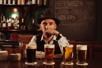 bartender in hat with a beard at bar counter with beer in glasses in pub