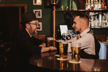 man has fun chatting with a bartender at bar counter with a glass of beer in a pub