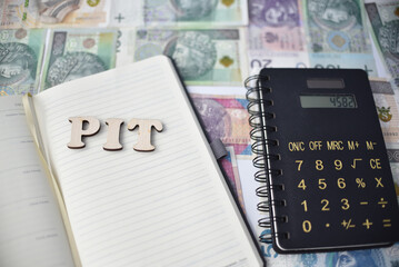 Kalkulator, kalendarz i napis PIT, w tle banknoty o roznych wartosciach, polskie zlotowki.