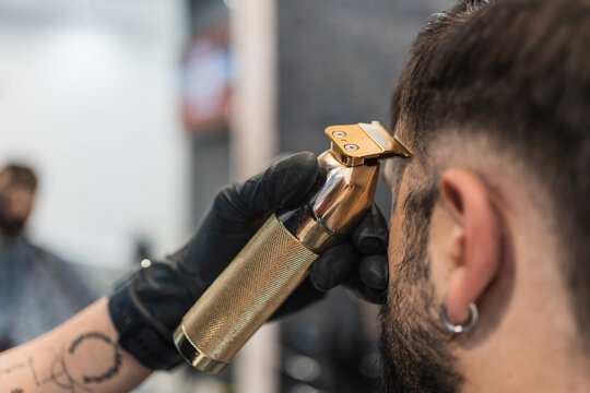 Close-up image of the gourmet golden hair clipper of the barber cutting a customer.