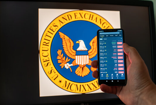 Kyiv, Ukraine - 06 June 2023: Man holds a smartphone with falling cryptocurrency quotes on Binance against the background of monitor with the SEC logo. S.E.C. sued and brought charges against Binance.