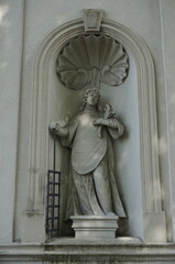 Fototapeta na wymiar Statue of Saint Lawrence in niche of Church of the Lord's Transfiguration facade. Ogrodzieniec, Poland.