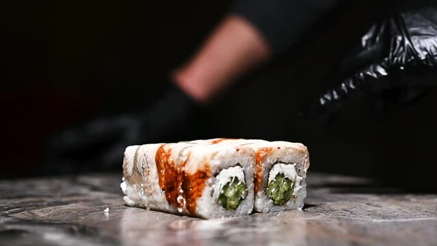 Process of cooking sushi roll Philadelphia. Sushi master cuts the roll into pieces with a knife.