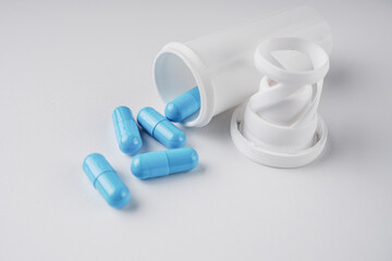 blue pills with container on white background