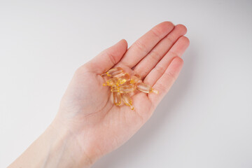 Yellow omega pills in hand on white background