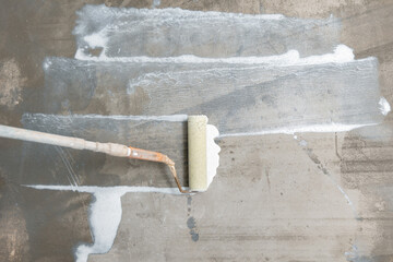 Closeup floor priming process, top view. Worker use primer on concrete floor before leveling,...