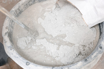 Closeup prepare cement for floor during renovation works, worker use handheld mixer