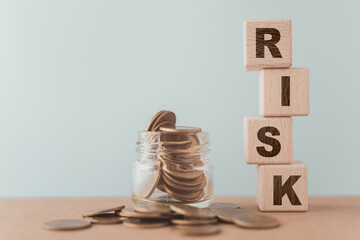 RISK text on wooden cube block and coins in jar for risk protection concept