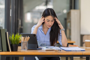 Portrait of tired young business Asian woman work with documents tax laptop computer in office. Sad, unhappy, Worried, Depression, or employee life stress concept
