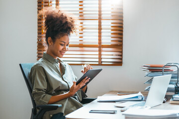 Happy African American teenage woman using a digital tablet and Laptop. Young leading businesswoman using a wireless tablet. Creative designer working in her House .