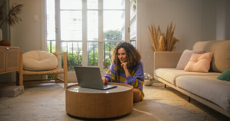 Portrait of Smiling Young Woman Working from Home on Laptop Computer in Sunny Cozy Apartment....