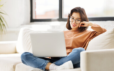 beautiful young woman uses laptop while sitting on sofa