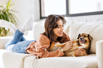 cheerful woman hugging her beloved pet dog at home on the couch.