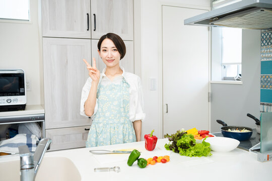 ピースサインをする若い女性　料理イメージ