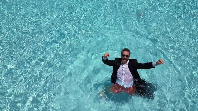 Excited businessman in pool water. Summer hot business. Business man success. Freelance work, distance online work. Summer excited business man in suit in sea water. Funny summer business. Crazy man.