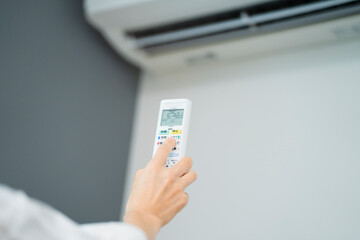 エアコンを操作する若い女性　ライフスタイルイメージ
